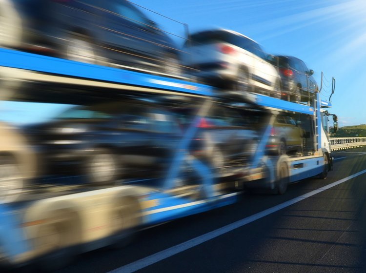 Biler på en autotransporter der kører på en landevej. 