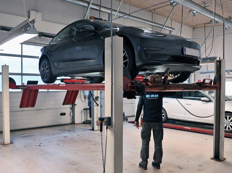 Testassistent står under grå Tesla på lift
