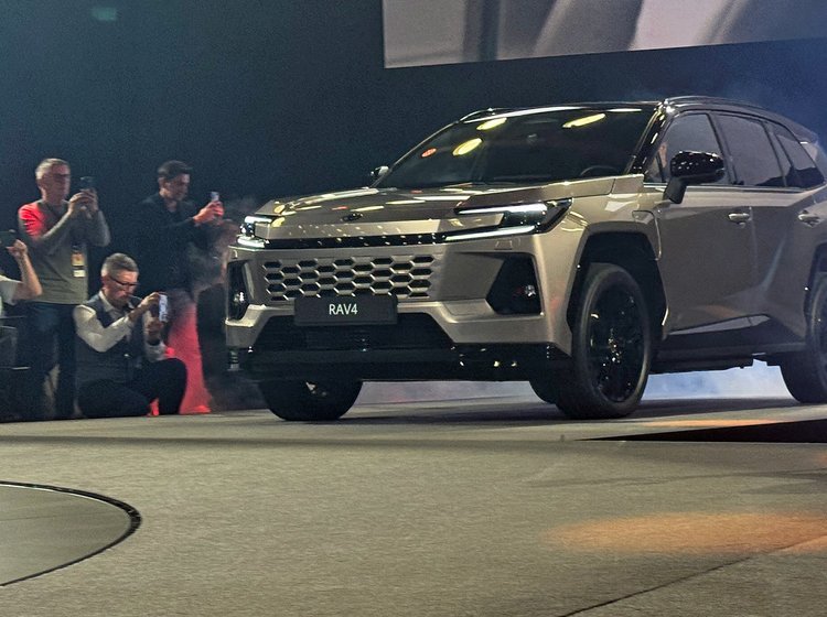 SUV skråt forfra med fotografer omkring.
