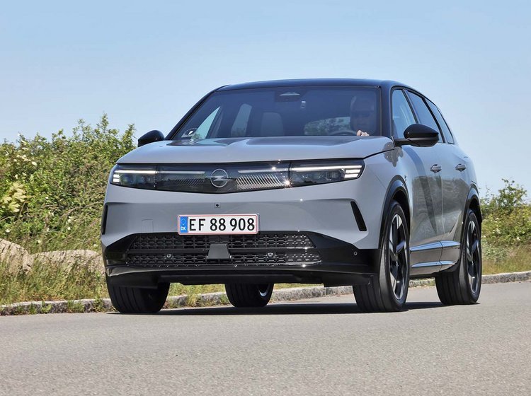 Opel Grandland kører i sving på vej med blå himmel i baggrunden