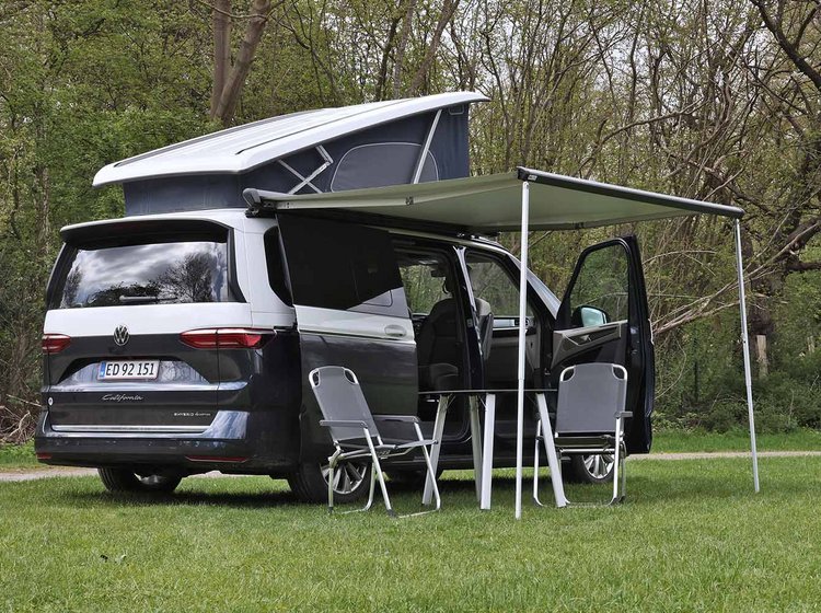 VW California med opslået tag og udslået markise holder på græsplæne