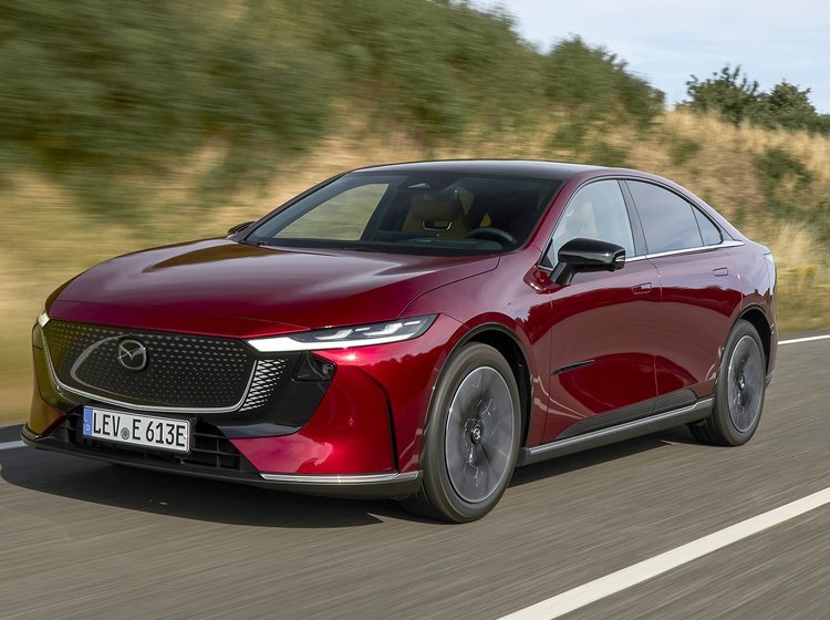 Elbilen Mazda 6e med rød metallak kører på en vej.