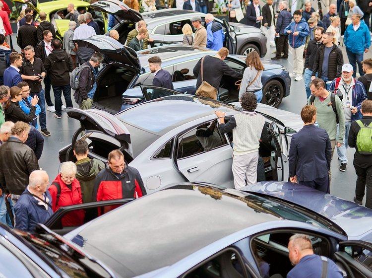 Biler og personer tæt sammen på biludstilling.