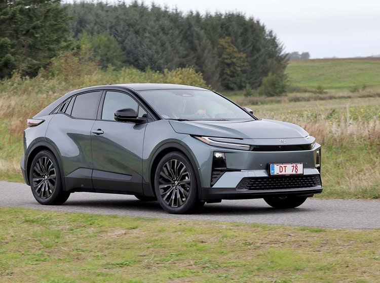 Toyota C-HR+ kører på landevej med træer og marker i baggrunden