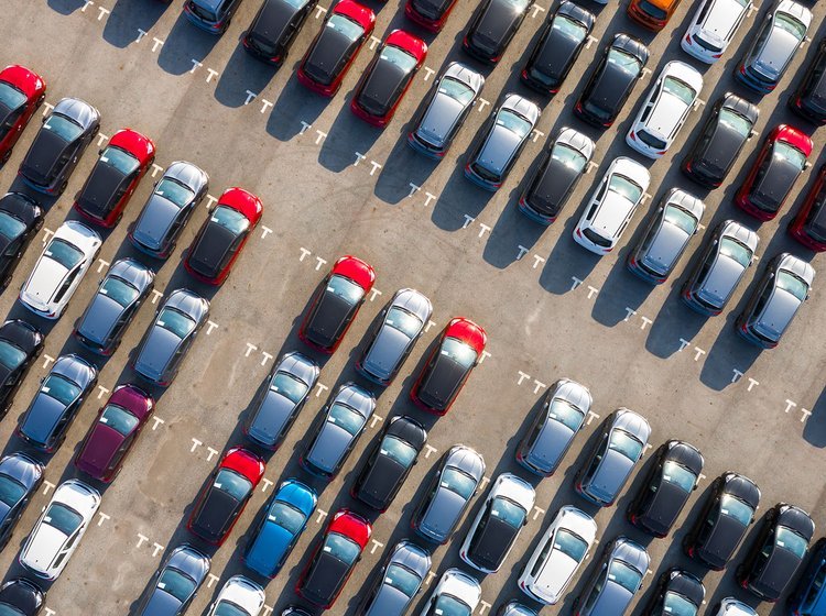 En masse biler i forskellige farver fotograferet fra luften på en parkeringsplads. 