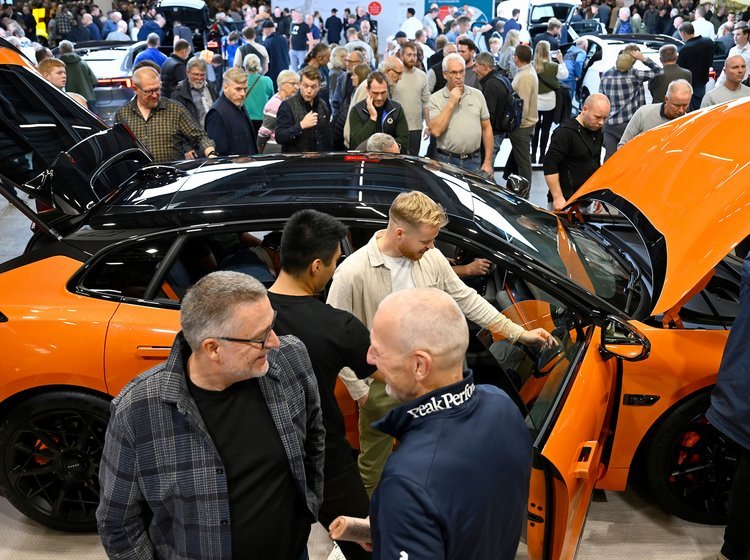 Menneskemylder rundt om orange bil.
