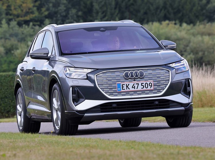 Audi Q4 e-tron set forfra, mens den kører på landevej med træer i baggrunden