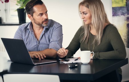 Et ægtepar sidder ved computer og taler sammen. 