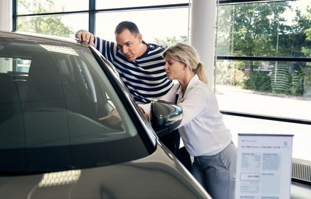 En mand og en kvinde kigger på bil hos en bilforhandler. 