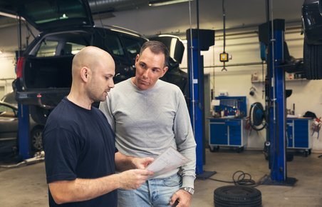 Mekaniker taler med kunde på et værksted. 