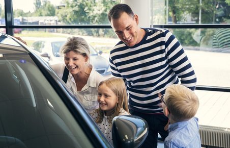Familie kigger på bil hos bilforhandler. 