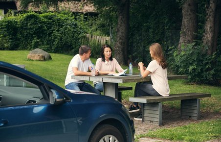 Familie på ferie har parkeret bilen og tager en pause på rasteplads. 
