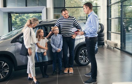 Familie taler med en bilhandler om at købe ny bil. 