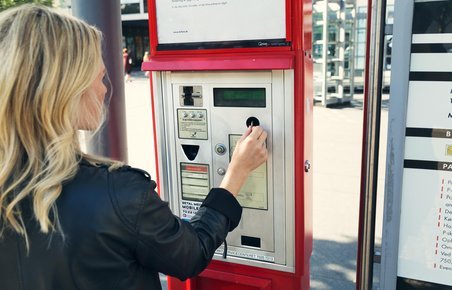 Kvinde betaler for parkering i en billetautomat.