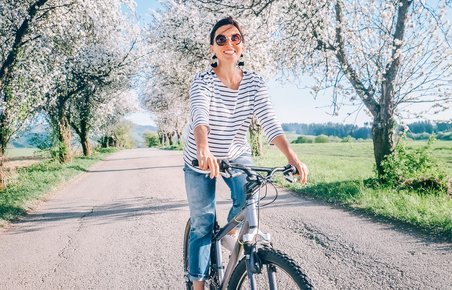 Kvinde på cykel, der kører under blomstrende æbletræer
