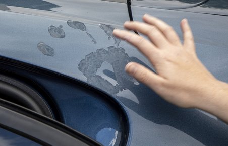På billedet ser du solcreme på bilens lak efter hånden har hvilet på bilen.