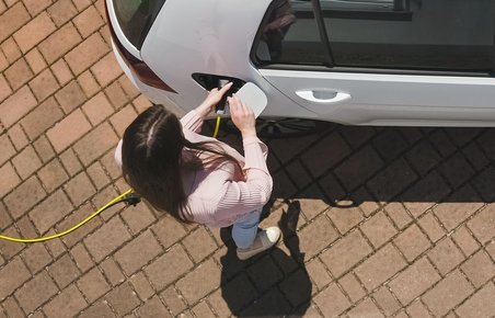 Kvinde lader en elbil udenfor.