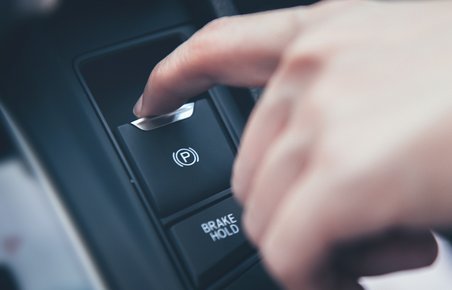 Elektronisk parkeringsbremse aktiveres i bil ved tryk på en knap. 