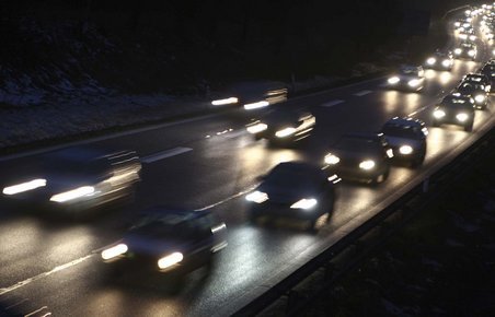 Bil med tændte forlygter kører i mørke på dansk motorvej