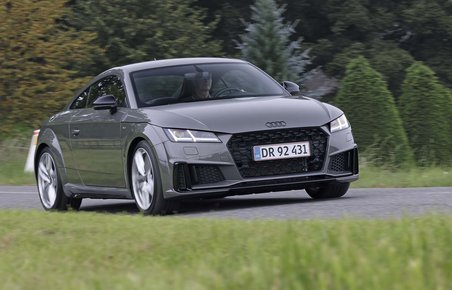 En Audi TT kører på en landevej med græs i forgrunden og træer i baggrunden