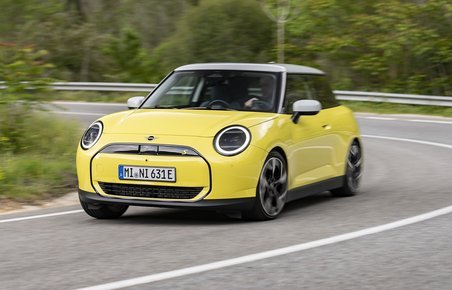 Gul Mini Cooper kører i et sving på en vej