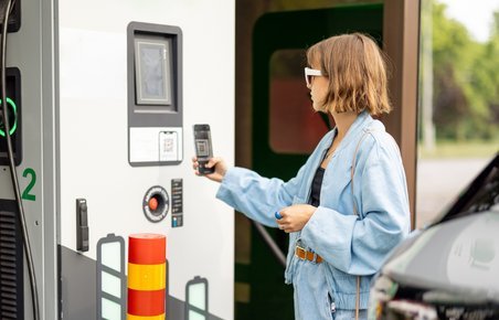 Kvinde scanner QR-kode ved ladestander