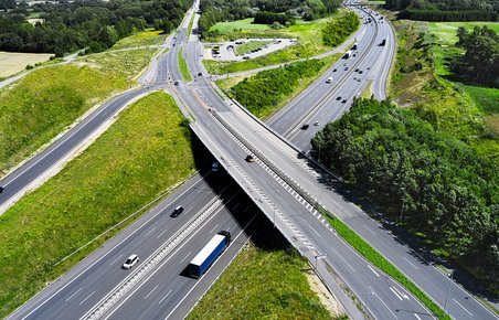 Overbliksbillede af en landevej og en motorvej der krydser hinanden. 