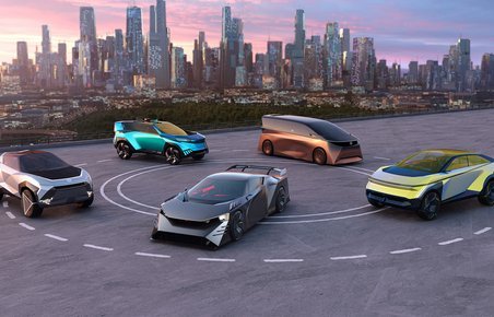 Fem futuristiske konceptbiler på asfalt med computertegnet højhusby i baggrunden.