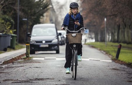 Kvinde cykler, mens hun ser på mobiltelefon