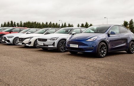 7 biler på stribe med blå Tesla Model Y i forggrunden.