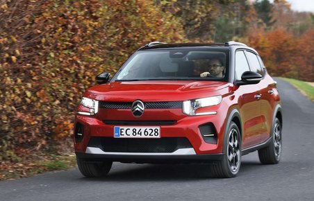 En rød Citroën ë-C3 kører i et sving på en landevej