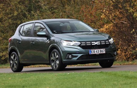 Dacia Sandero kører på landevej med træer i efterårsfarver i baggrunden
