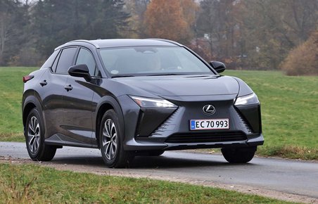 Lexus RZ set forfra, mens den kører på landevej med græs rundt om