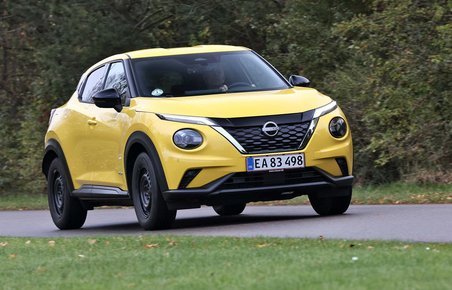 Gul Nissan Juke kører på landevej med træer i baggrunden