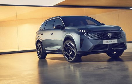Peugeot E-5008 elbilen står med en elegant bygning i baggrunden. 