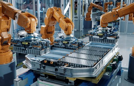Produktion af batterier. Orange robotter samler et bilbatteri. 