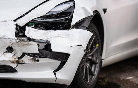 Skade på Tesla Model 3. Hvid bil med ødelagt forkofanger. 