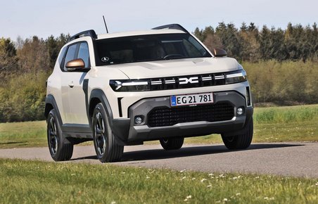 Dacia Duster set forfra, mens den kører på landevej med træer i baggrunden
