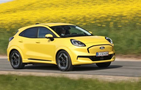 Gul Ford Puma kører på vej med rapsmarker i baggrunden