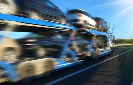Biler på en autotransporter der kører på en landevej. 