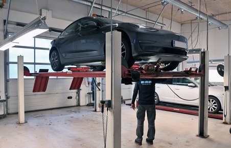 Testassistent står under grå Tesla på lift