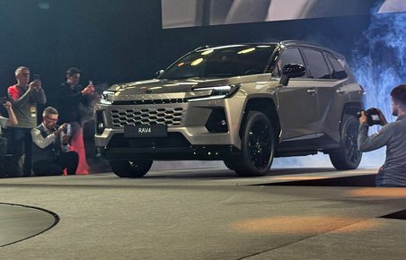 SUV skråt forfra med fotografer omkring.
