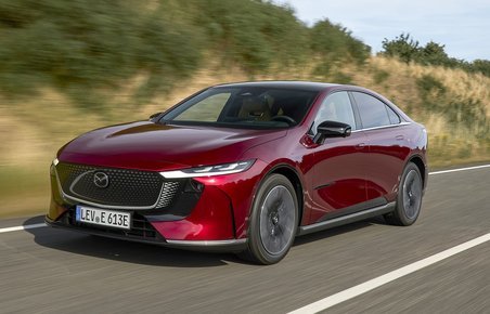 Elbilen Mazda 6e med rød metallak kører på en vej.