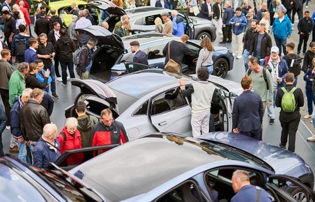 Biler og personer tæt sammen på biludstilling.
