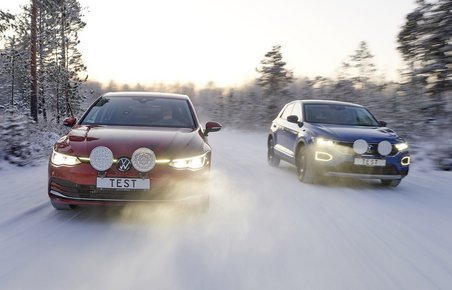 To biler kører på veje fuldkommen dækket af sne. 