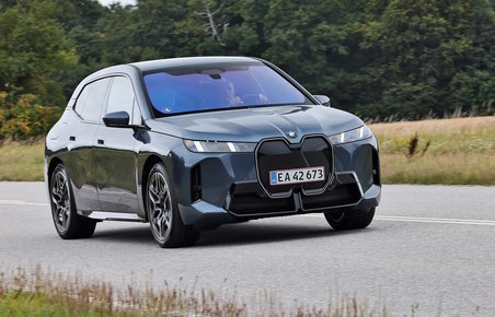 BMW iX set skråt forfra, mens den kører på en landevej