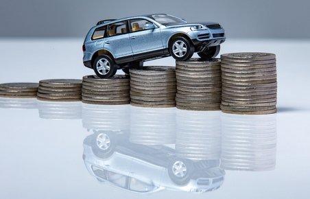 Blå modelbil kører op ad stabel mønter
