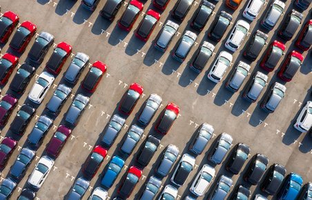 En masse biler i forskellige farver fotograferet fra luften på en parkeringsplads. 