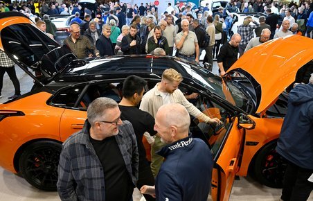 Menneskemylder rundt om orange bil.