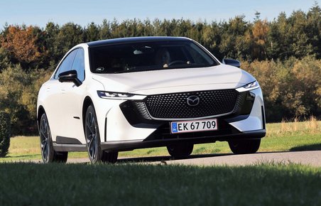 Mazda 6e set forfra, mens den kører på en landevej med træer i baggrunden